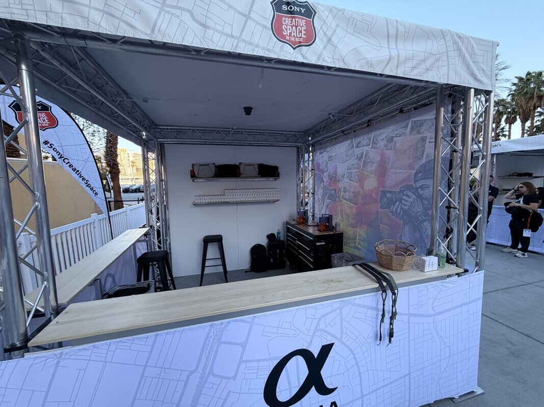 White truss-built brand booth with map-print wrap and gear displays at an outdoor brand roadshow