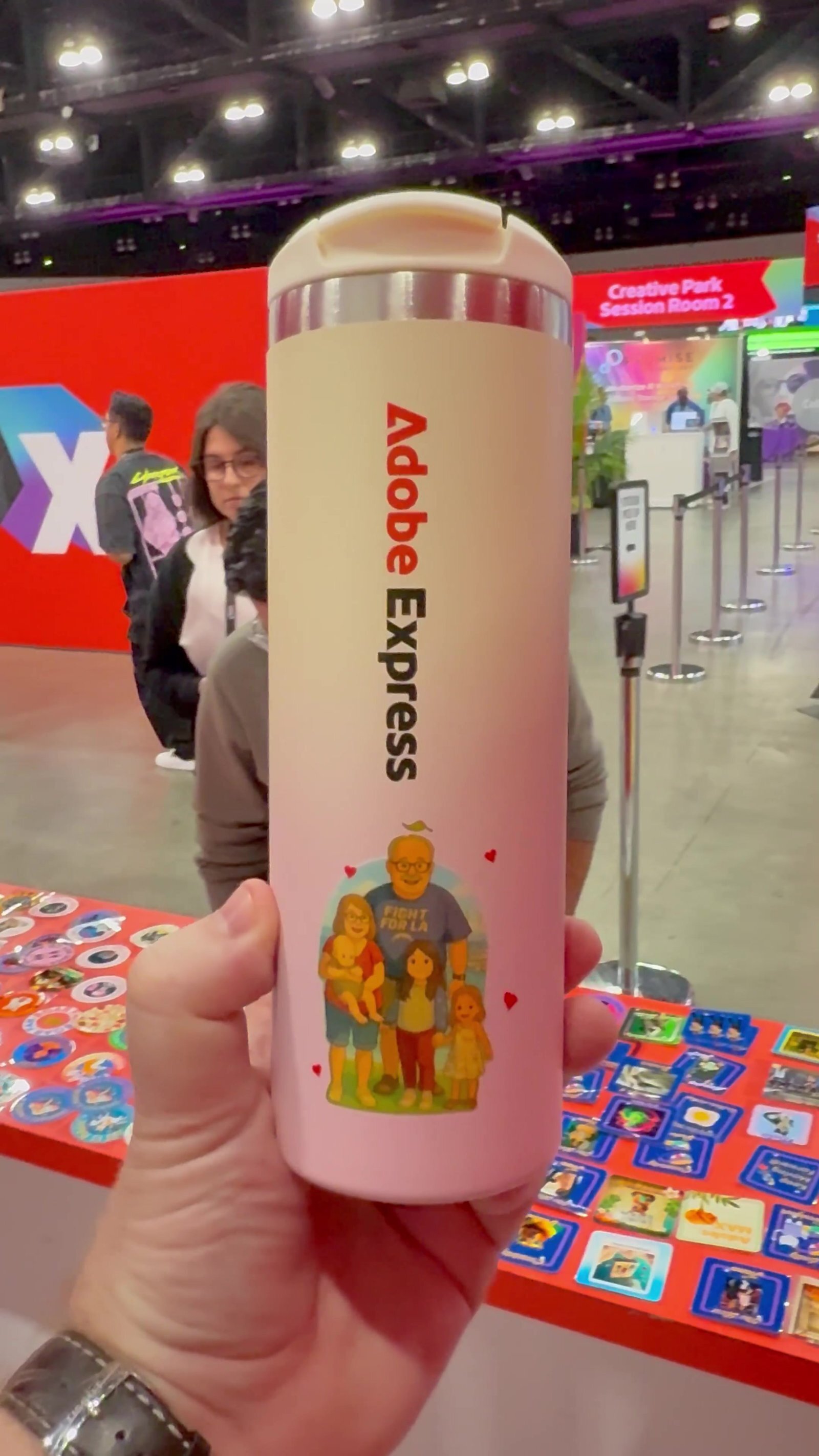 Hand holding a gradient tumbler customized with a full-color illustrated decal at a creative conference